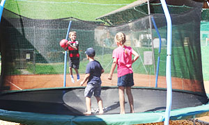 drei Kinder mit Ball im Trampolin